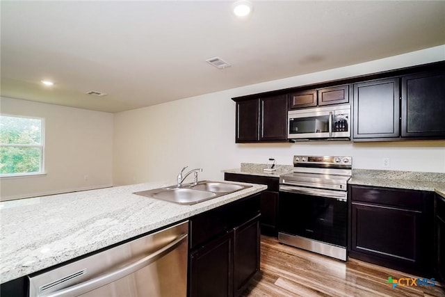 613 S 24th St, Temple, TX 76501 - kitchen featuring light wood-style flooring, a sink, stainless steel appliances, visible vents, and light stone countertops