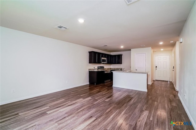 613 S 24th St, Temple, TX 76501 - kitchen with a kitchen island with sink, dark wood-type flooring, stainless steel microwave, light countertops, and recessed lighting