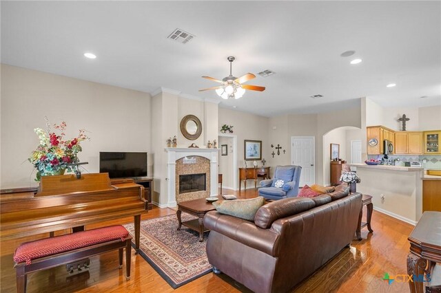 301 Deerchase, Victoria, TX 77901 - living room with arched walkways, a ceiling fan, light wood-type flooring, a tiled fireplace, and recessed lighting