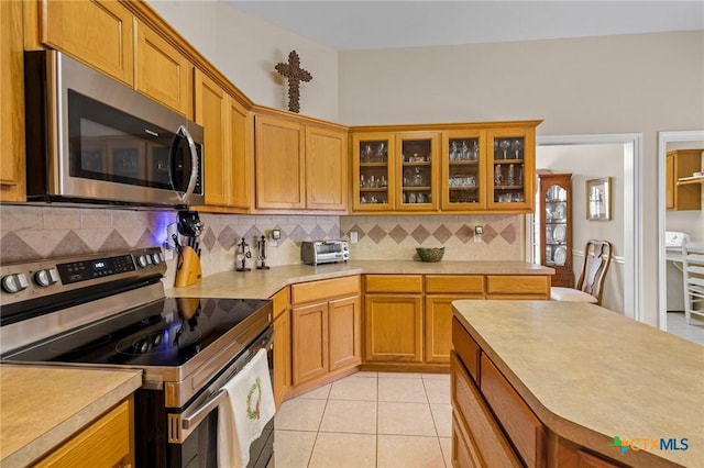 301 Deerchase, Victoria, TX 77901 - kitchen with stainless steel appliances, light countertops, tasteful backsplash, glass insert cabinets, and brown cabinetry