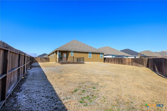 rear view of house featuring a fenced backyard and a lawn