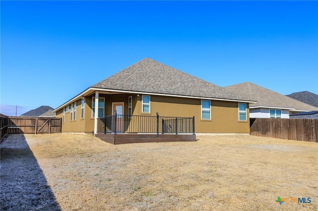 back of property with a fenced backyard, roof with shingles, and stucco siding