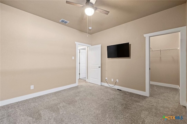 unfurnished bedroom with a spacious closet, carpet, visible vents, and baseboards