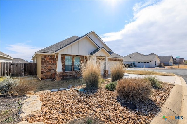 view of front of home featuring stone siding, board and batten siding, and fence