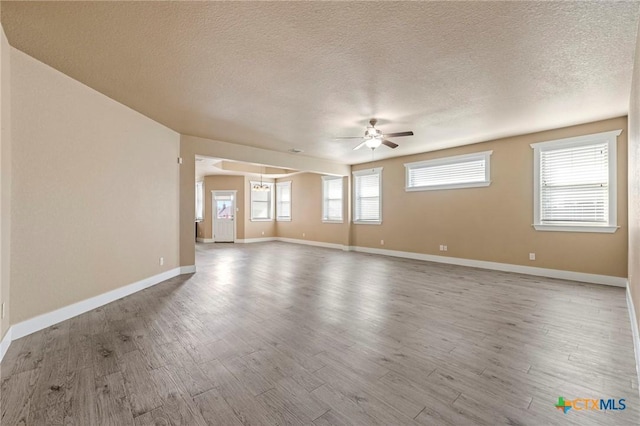 unfurnished room with ceiling fan, a textured ceiling, baseboards, and wood finished floors