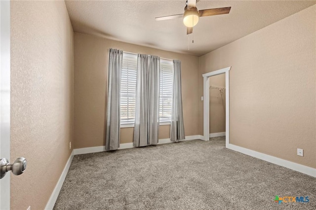 spare room with ceiling fan, carpet floors, a textured wall, and baseboards