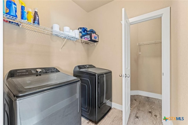 laundry room featuring laundry area, washer and clothes dryer, light wood-type flooring, and baseboards