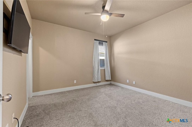 carpeted spare room with a textured ceiling, a ceiling fan, and baseboards