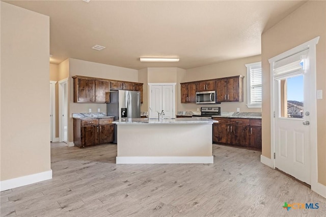 kitchen with dark brown cabinetry, visible vents, light wood-style floors, light countertops, and appliances with stainless steel finishes