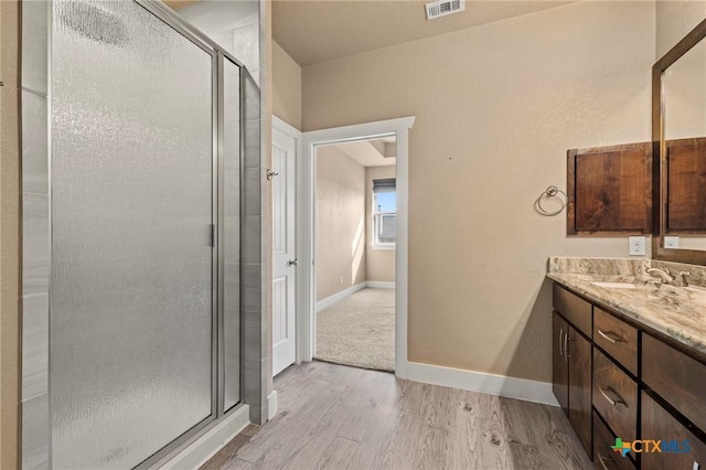 full bathroom with a stall shower, vanity, baseboards, and wood finished floors