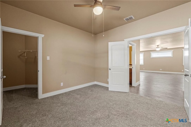 empty room with ceiling fan, carpet floors, visible vents, and baseboards