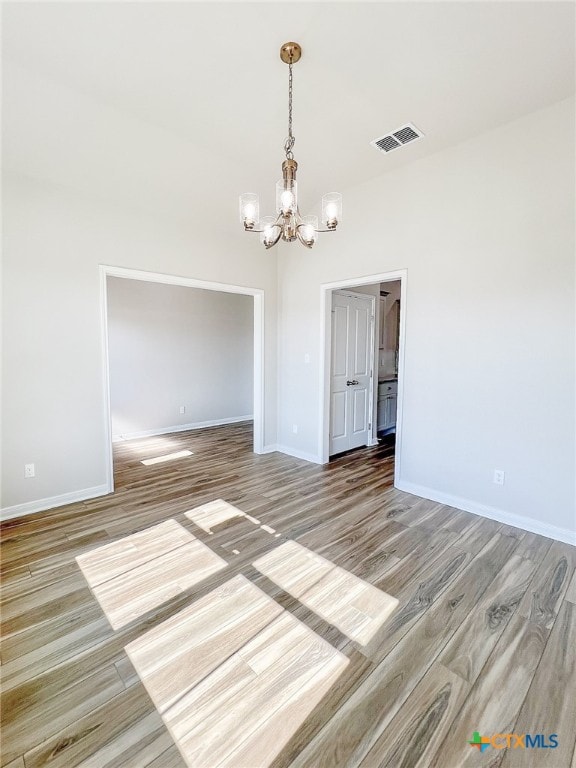 empty room featuring hardwood / wood-style flooring and an inviting chandelier