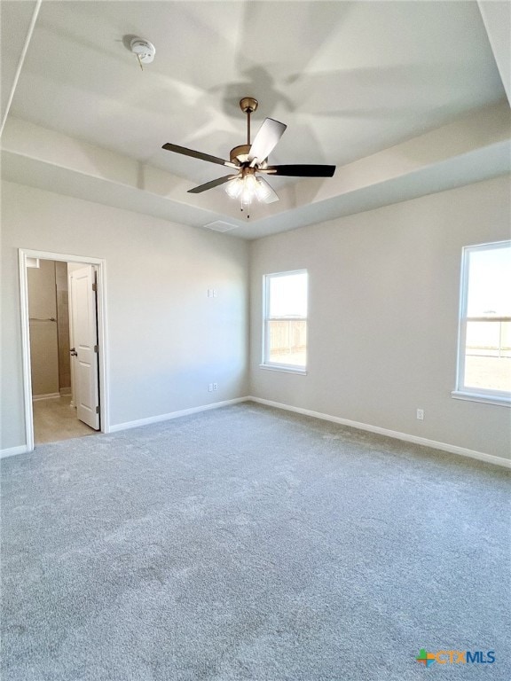 carpeted empty room featuring ceiling fan and a tray ceiling