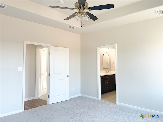 unfurnished bedroom with ensuite bath, light carpet, ceiling fan, and sink