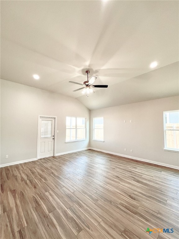 spare room with ceiling fan, a healthy amount of sunlight, light wood-type flooring, and vaulted ceiling