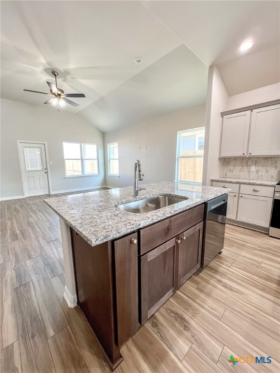 kitchen with sink, white cabinets, stainless steel dishwasher, lofted ceiling, and light hardwood / wood-style flooring