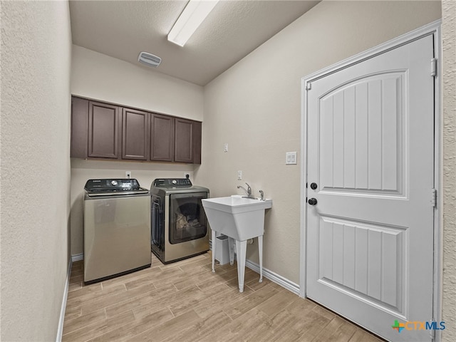 1306 Torino St, Harker Heights, TX 76548 - laundry area with light wood-style floors, washer and dryer, cabinet space, baseboards, and a textured wall