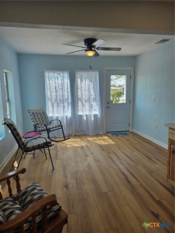 interior space featuring a textured ceiling, light wood-type flooring, and ceiling fan