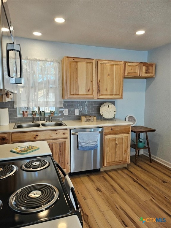 kitchen featuring decorative backsplash, light wood-type flooring, appliances with stainless steel finishes, and sink