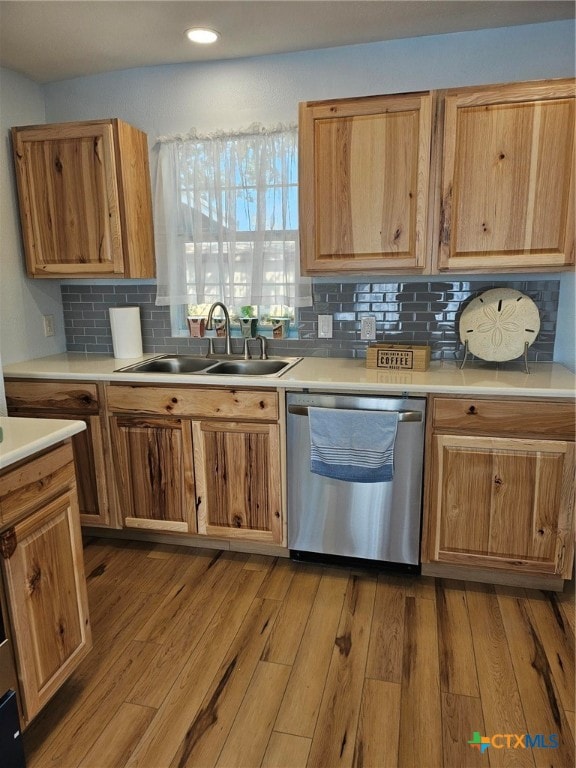 kitchen featuring hardwood / wood-style floors, tasteful backsplash, stainless steel dishwasher, and sink