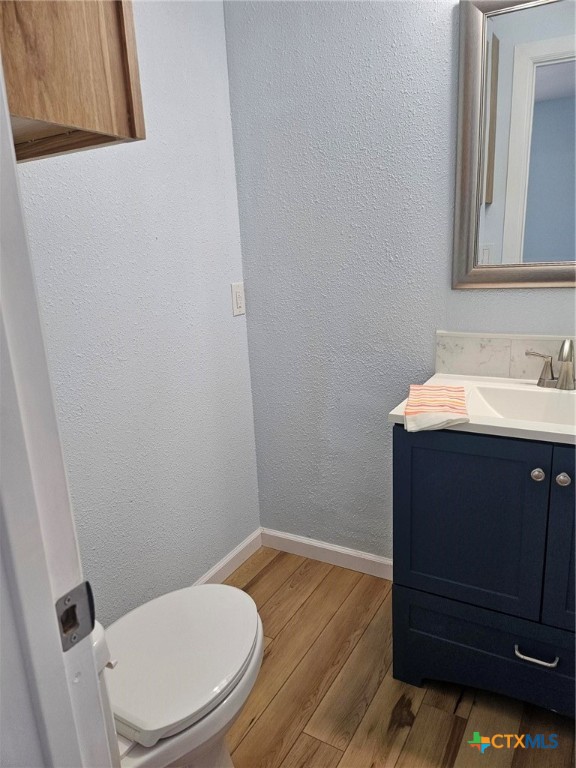 bathroom with toilet, vanity, and hardwood / wood-style flooring