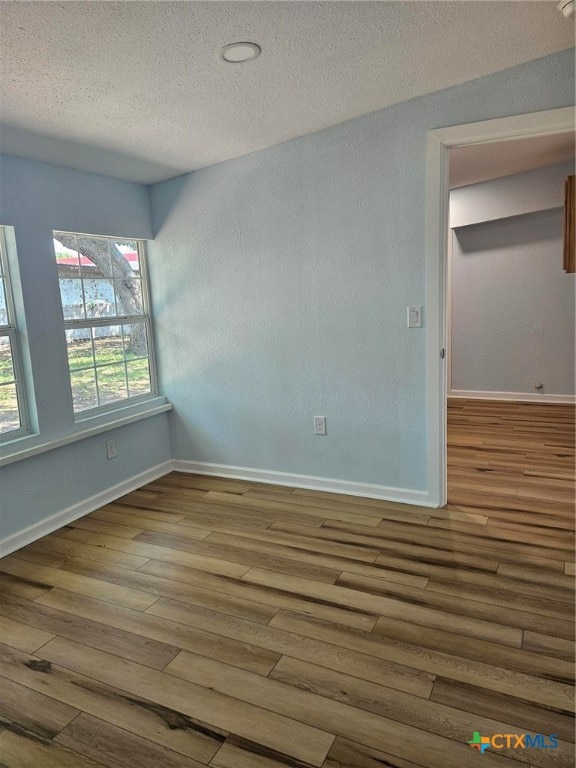 empty room with hardwood / wood-style floors and a textured ceiling