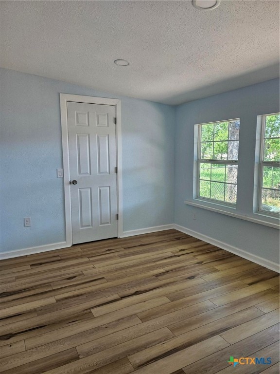 unfurnished room with wood-type flooring and a textured ceiling