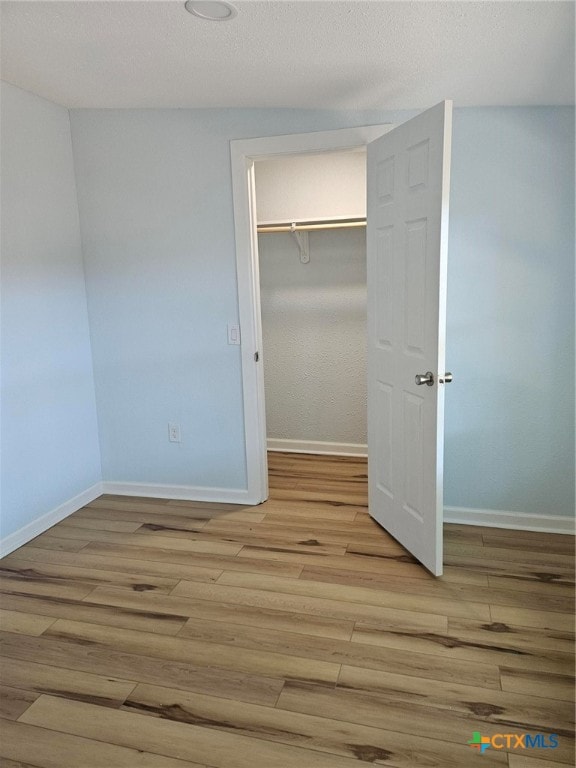 unfurnished bedroom featuring a closet, a textured ceiling, and light hardwood / wood-style flooring