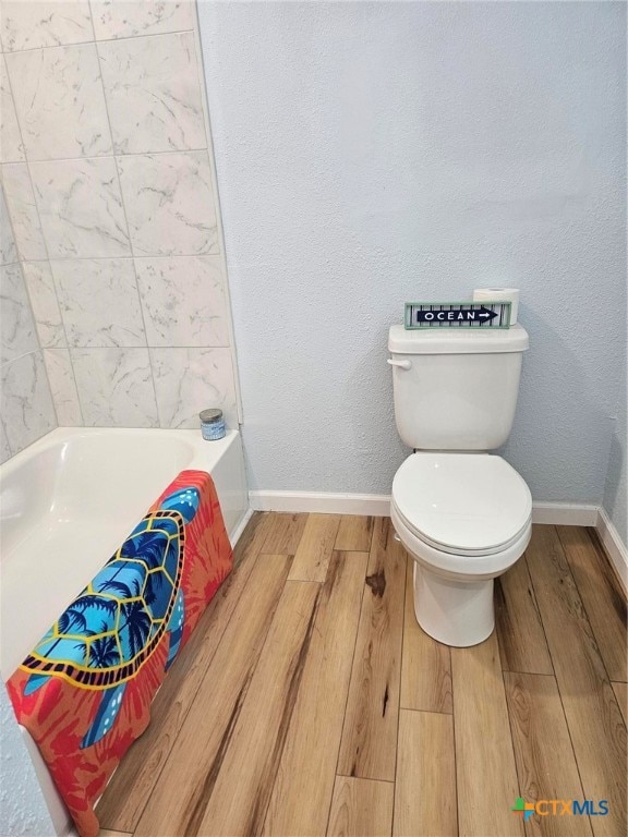 bathroom featuring toilet, hardwood / wood-style floors, and a bathtub