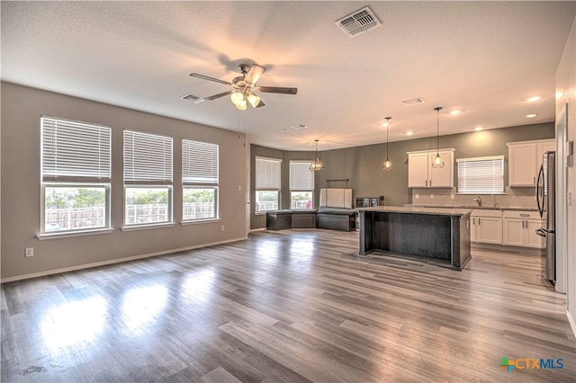 kitchen with decorative light fixtures, white cabinetry, ceiling fan with notable chandelier, a center island, and stainless steel refrigerator