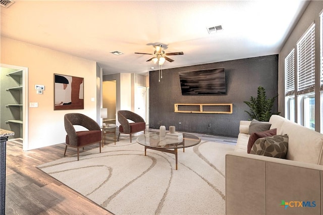 living room featuring a fireplace, light wood-type flooring, and ceiling fan