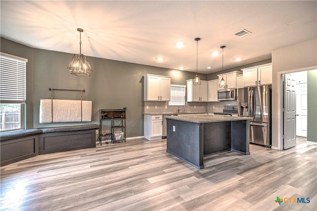 kitchen featuring light wood-type flooring, a center island, hanging light fixtures, and stainless steel appliances