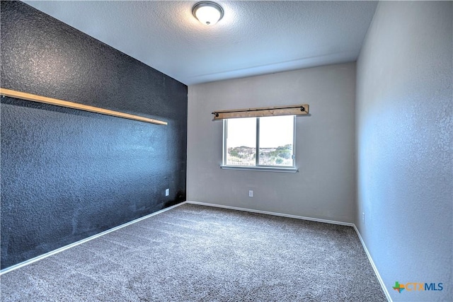 carpeted empty room featuring a textured ceiling