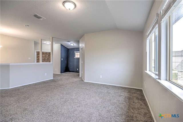 carpeted spare room with a textured ceiling and vaulted ceiling