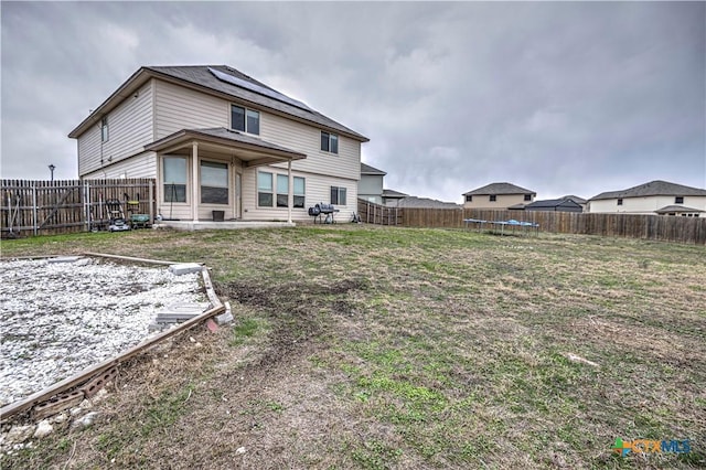 back of house featuring a yard and a trampoline