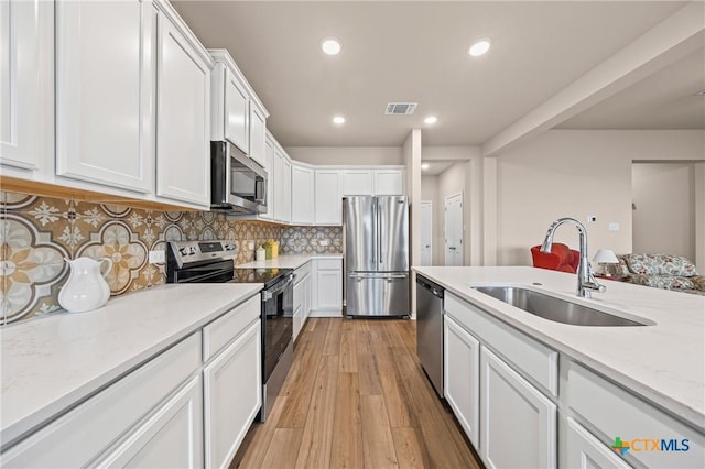 7109 Hammermill Ln, Temple, TX 76502 - kitchen featuring stainless steel appliances, white cabinetry, light wood-style floors, backsplash, and recessed lighting