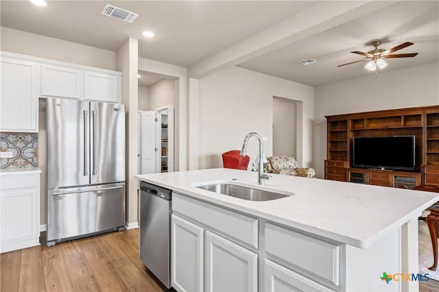 7109 Hammermill Ln, Temple, TX 76502 - kitchen with stainless steel appliances, open floor plan, white cabinets, ceiling fan, and a center island with sink