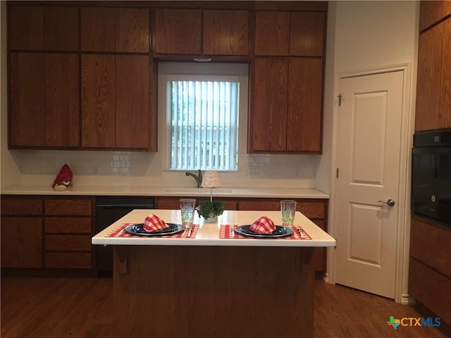 kitchen with decorative backsplash, black appliances, hardwood / wood-style floors, and sink