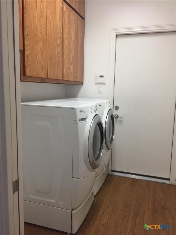 clothes washing area with cabinets, dark hardwood / wood-style floors, and washing machine and clothes dryer