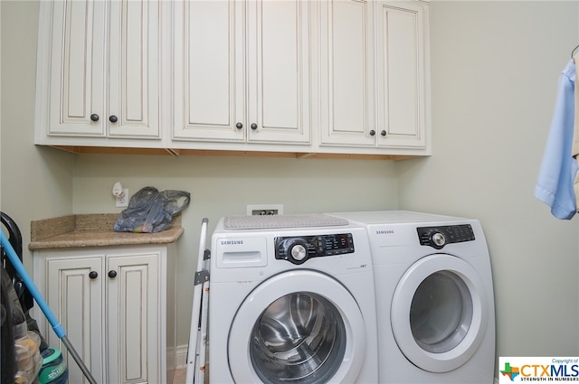 washroom featuring cabinets and washer and clothes dryer