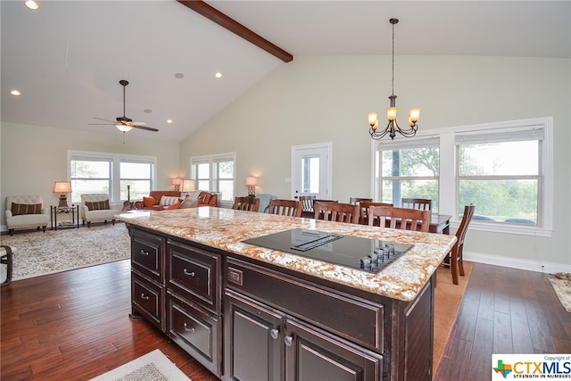 kitchen featuring black electric stovetop, a kitchen island, beam ceiling, dark hardwood / wood-style flooring, and a breakfast bar area