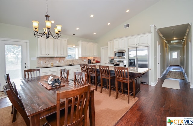 dining space featuring ornamental molding, a notable chandelier, dark hardwood / wood-style floors, high vaulted ceiling, and sink