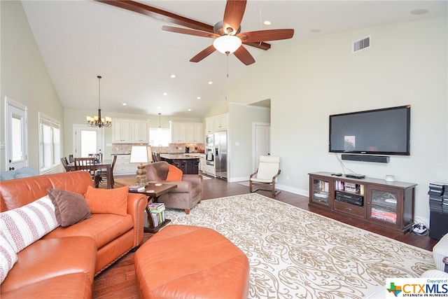 living room featuring dark wood-type flooring, ceiling fan with notable chandelier, and high vaulted ceiling