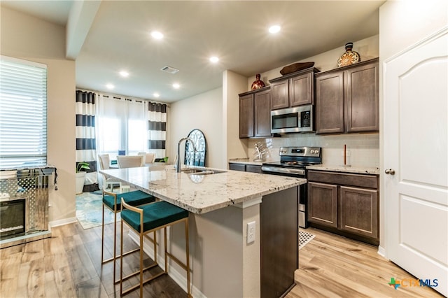 kitchen featuring a kitchen island with sink, light wood-type flooring, appliances with stainless steel finishes, and sink