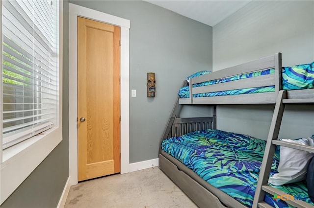 bedroom with concrete flooring and baseboards