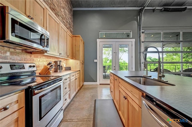 kitchen featuring concrete floors, a sink, decorative backsplash, french doors, and appliances with stainless steel finishes