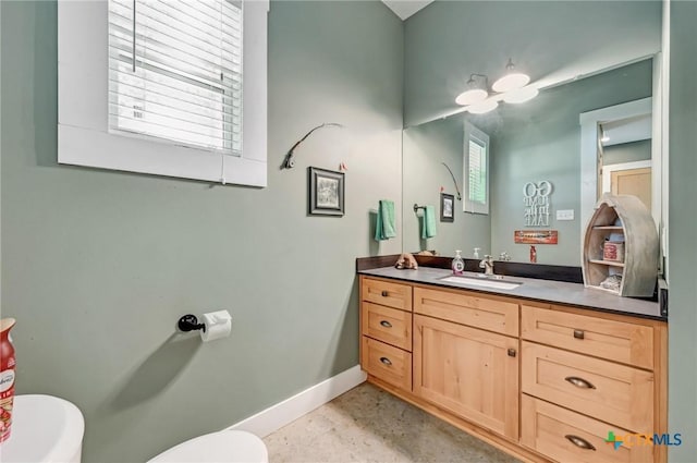 bathroom with concrete floors, baseboards, toilet, and vanity