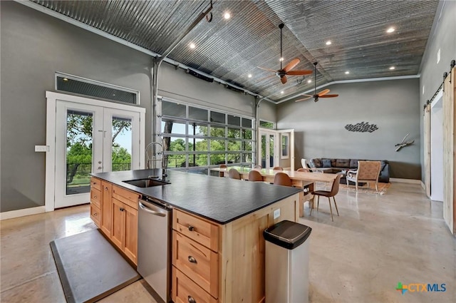 kitchen featuring a barn door, dark countertops, a sink, concrete flooring, and dishwasher