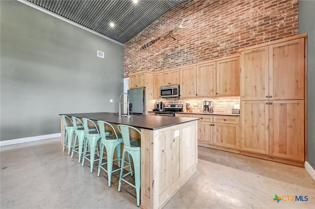 kitchen featuring concrete floors, light brown cabinetry, and stainless steel appliances