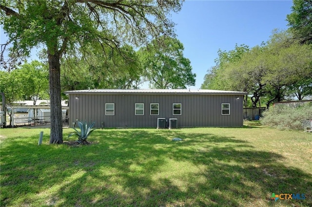 rear view of property featuring a lawn, central AC unit, and board and batten siding